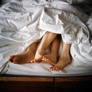 Couple's Feet Entangled in Bed